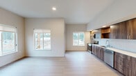 Located at 6914 NE 126th St in Vancouver, WA, this thoughtfully designed single-floor home offers three bedrooms, two bathrooms, and a well-organized layout that maximizes everyday comfort. The open-concept living, dining, and kitchen area forms the heart of the home, bathed in natural light from multiple windows. The kitchen stands out with rich walnut-toned cabinetry, open shelving, a classic white tile backsplash, light quartz countertops, and a full suite of stainless steel appliances. Light wood-tone luxury vinyl plank flooring flows consistently throughout the entire home, enhancing the clean, modern aesthetic. A glass door off the kitchen opens directly onto a private patio, extending the living space outdoors. The spacious primary bedroom features dual windows that invite abundant natural light, while the additional bedrooms offer bright, neutral spaces with outdoor views. Four closets — including a generously sized walk-in with wire shelving — provide ample storage. The bathrooms are clean and functional, with a dedicated walk-in shower. A hallway laundry area houses a stacked washer and dryer alongside the water heater, optimizing space efficiently. The overall ambiance is fresh, contemporary, and move-in ready.