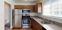 This single-floor residence is thoughtfully laid out across several interconnected rooms, offering a practical and comfortable living environment. The kitchen is a functional highlight, featuring warm medium-toned wood cabinetry, stainless steel appliances including a gas range, over-the-range microwave, refrigerator, and dishwasher, complemented by granite-look countertops and a stainless steel sink positioned beneath a window that allows natural light to fill the space. Hardwood flooring runs throughout the kitchen, adding warmth and durability.

The living area is generously proportioned, finished with neutral-toned carpet and bright white walls. A sliding glass door with vertical blinds opens to an outdoor area, while an additional window allows ample natural light. The space connects openly to the kitchen via a defined architectural passageway.

The bedrooms are carpeted and well-sized, each with access to natural light through standard windows. One bedroom features dual bifold closets, providing notable storage capacity. The full bathroom is clean and neatly appointed with a white vanity, mirrored medicine cabinet, tiled flooring, and a tub-shower combination. Throughout the residence, neutral finishes and clean lines create a cohesive, move-in-ready atmosphere.