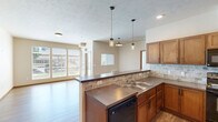 Located at 13313 E Fourth Ave in Spokane Valley, WA, this single-floor residence offers a thoughtfully designed layout with 1 bedroom, 2 bathrooms, and dedicated laundry. The kitchen is a standout feature, outfitted with warm wood cabinetry, a stone tile backsplash, laminate flooring, and a full suite of black appliances including a range, microwave, dishwasher, and refrigerator. A pendant light adds a contemporary touch over the workspace. The living area is bright and open, with large windows and a glass door that invite generous natural light and outdoor views. The entryway is welcoming, with stylish ceiling lighting and durable laminate flooring that extends throughout the main areas. The bedroom features plush carpeting, a window with a neighborhood view, and a baseboard heating unit. The hallway connects seamlessly to both bathrooms — one featuring wood-look flooring with a soaking tub, and the other with a wood-toned vanity with stone countertop. An in-unit laundry room accommodates a full-size washer and dryer with overhead shelving. Warm neutral tones, wood-trimmed doors, and consistent finishes throughout create a cohesive and comfortable living environment.