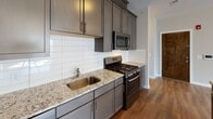 This well-designed 2-bedroom, 2-bathroom residence at 321 S Broad Street in Elizabeth, NJ offers a thoughtfully laid-out single-floor plan with a clean, modern aesthetic throughout. The open-concept living area is anchored by rich wood-style flooring, neutral toned walls, and multiple windows that invite generous natural light, creating a bright and welcoming atmosphere.

The kitchen is a standout feature, boasting dark gray shaker-style cabinetry, granite countertops, a classic white subway tile backsplash, a peninsula with additional counter space, and a full suite of stainless steel appliances including a gas range, microwave, dishwasher, and a French door refrigerator with an in-door ice and water dispenser.

Both bedrooms are generously sized, finished with plush wall-to-wall carpeting, and benefit from multiple windows with blinds that offer an abundance of natural light. At least one bedroom includes a dedicated walk-in closet for added storage convenience.

The two bathrooms are well-appointed with clean, modern finishes. One features a tiled tub-shower combination with a warm stone-look surround and a vanity with a framed mirror, while the second showcases a glass-enclosed walk-in shower with large-format slate-style tile and matching floor tile, lending a sleek, contemporary feel.
