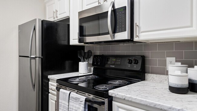 Esta moderna cocina con electrodomésticos de acero inoxidable, elegantes gabinetes blancos y un elegante protector contra salpicaduras de azulejos tipo metro es perfecta para cocinar y entretener en casa. - Sedona Peaks