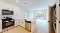 Located at 327 E Kennedy St in Spartanburg, South Carolina, this modern single-floor residence combines clean design with thoughtful functionality. The open-concept kitchen serves as a central highlight, featuring white shaker cabinetry with matte black hardware, a classic subway tile backsplash, quartz countertops, a peninsula with an undermount sink, and a full suite of stainless steel appliances. A contemporary multi-bulb pendant light anchors the space, which flows seamlessly into a bright living area lined with large windows offering lush outdoor views. Light-toned hardwood-style flooring runs consistently throughout, enhancing the airy, cohesive feel of the home. The bedrooms are generously proportioned, each benefiting from large windows that invite abundant natural light and neighborhood views; one room includes a ceiling fan with light fixture. A spacious walk-in closet with built-in shelving and a window adds practical storage. The primary bathroom features a white tile walk-in shower with sliding glass doors, a granite-topped vanity, and wire shelving, while a secondary bathroom offers a tub-shower combo and matching granite vanity. Matte black door hardware and fixtures provide a consistent modern accent throughout the entire residence.