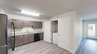 Located at 13135 Masons Bridge Rd in Woodbridge, VA, this single-floor, 3-bedroom, 2-bathroom residence offers a well-designed layout with modern finishes throughout. Wood-look plank flooring runs continuously across all rooms, lending a cohesive and clean aesthetic to the entire space.

The combined kitchen and living area serves as the heart of the home. The kitchen is equipped with rich dark-toned cabinetry, light granite-style countertops, black appliances including a range and dishwasher, and a single-basin sink. A dedicated in-unit laundry closet is conveniently positioned just off the kitchen. The open living area is bright and spacious, with neutral walls and windows that bring in natural light and views of the surrounding community.

Three bedrooms provide comfortable accommodations, each featuring windows with blinds and easy access to closet storage. Two well-appointed closets offer built-in shelving for organized storage. The primary bedroom is a generous size, providing ample room for a full furniture arrangement.

Both bathrooms are finished with granite-style vanity tops, dark wood cabinetry, wood-look flooring, and a shower-tub combination with a curved curtain rod. A connecting hallway ties all rooms together efficiently. The unit's clean, contemporary design makes it a functional and attractive residence.