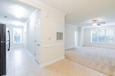 This single-story residence offers a well-designed, open floor plan that connects the main living areas seamlessly. The living room is finished with plush carpeting, crown molding, and a ceiling fan with a light fixture, while multiple windows allow natural light to fill the space. An adjoining dining area features tile flooring, a chandelier, and classic chair rail molding along the walls, with direct sightlines into the kitchen.

The kitchen is equipped with rich wood cabinetry, granite countertops, a stainless steel sink, and tile flooring, complemented by a tall window that brings in additional natural light. A secondary utility or laundry area mirrors the kitchen's finishes, featuring matching cabinetry, granite surfaces, and a louvered closet door.

The bedrooms are carpeted and bright, each with large windows fitted with blinds offering views of surrounding greenery, and paneled closet doors providing ample storage. The bathroom is appointed with granite countertops, tile flooring, a tub and shower combination, and accessibility-focused grab bars throughout. Neutral warm tones and consistent trim details unify the overall aesthetic of the space.