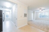 This single-story residence offers a well-designed, open floor plan that connects the main living areas seamlessly. The living room is finished with plush carpeting, crown molding, and a ceiling fan with a light fixture, while multiple windows allow natural light to fill the space. An adjoining dining area features tile flooring, a chandelier, and classic chair rail molding along the walls, with direct sightlines into the kitchen.

The kitchen is equipped with rich wood cabinetry, granite countertops, a stainless steel sink, and tile flooring, complemented by a tall window that brings in additional natural light. A secondary utility or laundry area mirrors the kitchen's finishes, featuring matching cabinetry, granite surfaces, and a louvered closet door.

The bedrooms are carpeted and bright, each with large windows fitted with blinds offering views of surrounding greenery, and paneled closet doors providing ample storage. The bathroom is appointed with granite countertops, tile flooring, a tub and shower combination, and accessibility-focused grab bars throughout. Neutral warm tones and consistent trim details unify the overall aesthetic of the space.
