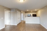 Located at 3500 S Grand Slam Ave in Sioux Falls, South Dakota, this 2-bedroom, 1-bathroom residence offers a thoughtfully designed single-floor layout with a clean, modern aesthetic throughout. The open-concept living and kitchen area serves as the heart of the home, where light-toned luxury vinyl plank flooring flows seamlessly underfoot. The kitchen features white cabinetry, dark countertops, a peninsula with a breakfast bar overhang, a built-in dishwasher, refrigerator, and microwave — all finished in black — providing both style and functionality. Recessed lighting illuminates the space, while a sliding glass door off the living area adds natural light and outdoor access. The primary bedroom is a generously sized retreat with durable wood-look flooring, neutral warm-toned walls, and direct access to a closet. The second bedroom is carpeted, offering a softer, cozier feel. The full bathroom is well-appointed with white cabinetry, a stone-look countertop, a large mirror, and a full tub-shower combination. A dedicated laundry area houses a full-size washer and dryer with overhead shelving. The space combines practical amenities with a neutral, move-in-ready aesthetic throughout.
