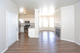Located at 9500 Osuna Rd NW in Albuquerque, New Mexico, this single-story residence offers a well-designed, open layout that seamlessly connects the main living areas. The living room is anchored by a tile-surround fireplace with a classic white mantel, complemented by rich hardwood-style flooring and crown molding that adds an elegant finishing touch throughout.

Adjacent to the living room, a charming bay-windowed dining area floods the space with natural light and features a stylish chandelier overhead, creating an inviting atmosphere for everyday dining or entertaining.

The kitchen is well-appointed with white shaker-style cabinetry, granite-look countertops, and a full suite of stainless steel appliances including a refrigerator, electric range, microwave, and double-basin sink. A peninsula counter provides additional prep space and opens toward the dining area for easy flow.

The bedrooms are generously sized, each carpeted for comfort and fitted with blinds that offer outdoor views of surrounding greenery. Crown molding and ceiling fans are present in select rooms, enhancing both style and comfort.

The bathrooms are clean and functional, featuring tiled tub-shower combinations, wood-style flooring, granite-look vanity countertops, and brushed nickel fixtures. The primary bathroom includes access to a walk-in closet with built-in shelving.