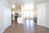 Located at 9500 Osuna Rd NW in Albuquerque, New Mexico, this single-story residence offers a well-designed, open layout that seamlessly connects the main living areas. The living room is anchored by a tile-surround fireplace with a classic white mantel, complemented by rich hardwood-style flooring and crown molding that adds an elegant finishing touch throughout.

Adjacent to the living room, a charming bay-windowed dining area floods the space with natural light and features a stylish chandelier overhead, creating an inviting atmosphere for everyday dining or entertaining.

The kitchen is well-appointed with white shaker-style cabinetry, granite-look countertops, and a full suite of stainless steel appliances including a refrigerator, electric range, microwave, and double-basin sink. A peninsula counter provides additional prep space and opens toward the dining area for easy flow.

The bedrooms are generously sized, each carpeted for comfort and fitted with blinds that offer outdoor views of surrounding greenery. Crown molding and ceiling fans are present in select rooms, enhancing both style and comfort.

The bathrooms are clean and functional, featuring tiled tub-shower combinations, wood-style flooring, granite-look vanity countertops, and brushed nickel fixtures. The primary bathroom includes access to a walk-in closet with built-in shelving.