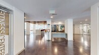 Located at Innslake Place in Glen Allen, Virginia, this single-floor amenity and leasing space offers a generously sized, open-concept layout designed for both functionality and style. The entry corridor features polished concrete floors, crisp white walls, and a welcoming reception desk, setting a clean and contemporary tone throughout.

The main gathering area is anchored by a striking wood-slat ceiling detail that adds warmth and visual texture, contrasting beautifully with the bright white walls and recessed lighting. A granite-topped bar counter with stylish upholstered barstools provides a comfortable social hub, while the adjacent kitchen features bold cobalt blue cabinetry, granite countertops, a white subway tile backsplash, and floating wood shelves — a vibrant yet refined design statement.

The lounge area is thoughtfully furnished with a neutral sofa, accent seating, and curated artwork, creating a relaxed and inviting atmosphere. Large floor-to-ceiling windows flood the space with natural light and offer direct views of the outdoor patio and pool area, seamlessly blending indoor and outdoor living. A foosball table adds a playful touch, reflecting the community-oriented spirit of the space. Throughout, the design balances modern aesthetics with warm, natural materials for a polished and welcoming environment.
