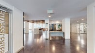 Located at Innslake Place in Glen Allen, Virginia, this single-floor amenity and leasing space offers a generously sized, open-concept layout designed for both functionality and style. The entry corridor features polished concrete floors, crisp white walls, and a welcoming reception desk, setting a clean and contemporary tone throughout.

The main gathering area is anchored by a striking wood-slat ceiling detail that adds warmth and visual texture, contrasting beautifully with the bright white walls and recessed lighting. A granite-topped bar counter with stylish upholstered barstools provides a comfortable social hub, while the adjacent kitchen features bold cobalt blue cabinetry, granite countertops, a white subway tile backsplash, and floating wood shelves — a vibrant yet refined design statement.

The lounge area is thoughtfully furnished with a neutral sofa, accent seating, and curated artwork, creating a relaxed and inviting atmosphere. Large floor-to-ceiling windows flood the space with natural light and offer direct views of the outdoor patio and pool area, seamlessly blending indoor and outdoor living. A foosball table adds a playful touch, reflecting the community-oriented spirit of the space. Throughout, the design balances modern aesthetics with warm, natural materials for a polished and welcoming environment.