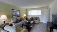 Located at 333 North Avenue in Secane, Pennsylvania, this single-floor residence offers a practical and comfortable layout designed for everyday living. The living room serves as the heart of the home, featuring a warm and inviting atmosphere with neutral-toned carpeting underfoot and a tasteful combination of green accent walls and crisp off-white paintwork. A large double-pane window allows natural light to pour into the space, creating a bright and airy feel throughout the day. The room provides ample space for seating arrangements centered around a dark wood coffee table, making it well-suited for both relaxing and entertaining. A baseboard heating unit along the wall ensures year-round comfort. Decorative touches, including framed wall art and coordinated accent pillows, contribute to the cohesive and tidy aesthetic of the interior. The single-story design ensures seamless, step-free access throughout the entire home, adding to the overall ease and convenience of the layout. This residence at 333 North Avenue presents a clean, move-in-ready living environment in the established community of Secane, PA.
