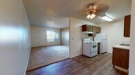 Located at 5050 E Fifth St in Tucson, Arizona, this single-story unit offers a functional and straightforward layout designed for comfortable everyday living. The open-concept living and kitchen area is one of the home's defining features, with durable wood-look flooring throughout the kitchen and entryway that transitions into plush carpeting in the living and sleeping areas. The kitchen is equipped with dark wood cabinetry, a white electric range, a refrigerator, and ample counter space, all beneath bright overhead lighting. A ceiling fan in the adjoining living area adds both comfort and style, while vertical blinds on the windows allow for adjustable natural light. The living room is generously sized with neutral-toned walls and a textured ceiling, creating a clean, move-in-ready atmosphere. The bedrooms feature soft carpeting, vertical-blind windows that let in natural light, and wall sconce lighting. Each bedroom is positioned near a full bathroom, both of which include a vanity with under-sink storage, a toilet, and a tub/shower combination with wood-look flooring. The overall layout is practical and well-organized, offering a comfortable living experience in a central Tucson location.