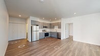 Located in Fairview, Oregon, this well-appointed 2-bedroom, 2-bathroom residence offers a thoughtfully designed single-floor layout with a clean, modern aesthetic throughout. The open-concept living and kitchen area serves as the heart of the home, with wood-look plank flooring and recessed lighting creating a warm, inviting atmosphere. The kitchen is outfitted with sleek gray cabinetry, white countertops, a subway tile backsplash, and a full suite of stainless steel appliances including a refrigerator, range, microwave, and dishwasher. The living area features multiple windows with blinds that invite natural light and include access to an exterior door. Both bedrooms are comfortably sized, with the spacious primary bedroom offering ample room for furnishings. Each bedroom features wood-look flooring, windows with blinds, and a wall-mounted HVAC unit for individualized climate control. The two bathrooms are finished in a consistent modern style, with gray vanity cabinetry, white countertops, large mirrors, and wood-look flooring. One bathroom includes a tub/shower combo, while the other features an elongated layout with additional accessibility hardware. A clean, well-lit hallway connects the living spaces to the private areas, completing this functional and contemporary home.
