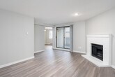 This single-floor residence offers a thoughtfully designed layout with contemporary finishes and a warm, neutral color palette throughout. The open living area is a standout feature, anchored by a classic white brick fireplace and complemented by durable wood-style flooring that extends throughout the home. A sliding glass door floods the space with natural light and provides direct access to a private balcony, creating a seamless indoor-outdoor connection. An adjoining area, equipped with a ceiling fan, adds versatile living space ideal for dining or a secondary lounge.

The galley-style kitchen is efficiently designed with white upper cabinetry, dark lower cabinets, light stone countertops, a subway tile backsplash, a stainless steel sink, and full-size appliances including a refrigerator and range.

Two well-proportioned bedrooms each feature wood-style flooring, neutral walls, and windows fitted with blinds that allow for ample natural light. Baseboard heating is present throughout the home for year-round comfort.

The residence includes two bathrooms: one featuring a tub-shower combination with white tile surround and a modern dark-wood vanity with a vessel-style sink, and a second with a walk-in shower stall and brushed nickel fixtures. Both bathrooms are finished with wood-style flooring for a cohesive aesthetic.