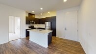 Located at 1056 E Philadelphia St in Ontario, CA, this single-story residence offers a thoughtfully designed open-concept floor plan that seamlessly connects the living and kitchen areas. The kitchen is a standout feature, showcasing rich dark cabinetry that reaches toward the ceiling, a crisp white quartz countertop island with an integrated sink, and a full suite of stainless steel appliances including a gas range, microwave, dishwasher, and refrigerator. A white tile backsplash adds a clean contrast to the bold cabinetry. Recessed lighting throughout enhances the modern aesthetic.

The spacious living area is finished with durable hardwood-style flooring and features a ceiling fan, adding both comfort and style. Natural light filters in through multiple windows fitted with blinds. The bedroom offers plush carpeting and generous natural light from dual windows. The primary bathroom is equipped with a dual-sink vanity topped with white quartz, dark cabinetry with ample drawer storage, and a shower-tub combo with sliding glass doors. A second bathroom mirrors the clean, modern finishes found throughout the unit. The overall design is cohesive, contemporary, and move-in ready.