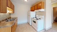 Located at 4265 Galley Rd in Colorado Springs, Colorado, this single-floor unit offers a straightforward and functional layout well-suited for comfortable everyday living. The kitchen is equipped with warm oak-toned cabinetry providing ample storage, a white electric range with overhead ventilation, a full-size refrigerator, and a sink with countertop workspace. Tile flooring in the kitchen adds durability and ease of maintenance. The living area is finished with plush carpeting that extends into the bedroom, creating a warm and cohesive feel throughout. Large windows fitted with vertical blinds allow generous natural light to filter in, brightening the interiors and highlighting the neutral, cream-toned walls. A wall-mounted air conditioning unit and baseboard heating ensure year-round climate comfort. The bathroom features a full tub-shower combination with chrome fixtures, a toilet, a vanity with an integrated sink, and a wood-framed mirror with medicine cabinet storage above — all finished in clean, neutral tones with tile flooring. Textured ceilings are consistent throughout the unit. The overall layout is compact yet efficient, making practical use of every area within the space.