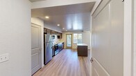 Located in Spokane, WA, this single-floor unit offers four bedrooms and two bathrooms within a well-organized layout. The open-concept kitchen and living area serves as the heart of the home, featuring rich dark cabinetry, a full suite of stainless steel appliances including a refrigerator, range, microwave, and dishwasher, and a freestanding center island with a light countertop — ideal for meal prep or casual dining. Light hardwood-style flooring extends throughout the main living area, adding warmth and continuity. A sliding glass door provides access to an outdoor space and brings in generous natural light. The bedrooms are carpeted for comfort; some feature windows with exterior views, while at least one room is finished with the same hardwood-style flooring as the main living area. The two bathrooms offer distinct configurations: one includes a walk-in shower stall with chrome fixtures, while the other features a full tub-shower combination, a vanity with a light countertop, and matching dark cabinetry. Multiple hallways connect the rooms efficiently, and textured ceilings are present throughout. Recessed lighting illuminates the kitchen and living spaces, enhancing the clean, functional aesthetic of this practical Spokane residence.
