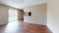 Located at 110 E Hawkins Pkwy in Longview, TX, this single-floor residence offers 2 bedrooms and 2 bathrooms within a well-organized layout. The open-concept living, dining, and kitchen area forms the heart of the home, anchored by rich wood-look flooring throughout the main living spaces. The living room features a tiled wood-burning fireplace and sliding glass doors that lead to a private patio, allowing natural light to fill the space. A built-in pass-through shelf adds a functional architectural detail between the living and kitchen areas. The kitchen is equipped with ample wood cabinetry, black appliances including a full-size refrigerator and range, a double sink, and a peninsula breakfast bar that connects seamlessly to the dining and living areas. Both bedrooms are carpeted for comfort and feature neutral walls with textured ceilings. The primary bedroom includes a dedicated walk-in closet, and the unit benefits from a total of five closets throughout, offering generous storage. Each bathroom includes a full tub-and-shower combination with white tile surrounds. Additional conveniences include an in-unit laundry area and a dedicated entrance. The overall aesthetic is clean and neutral, providing a functional and comfortable living environment.
