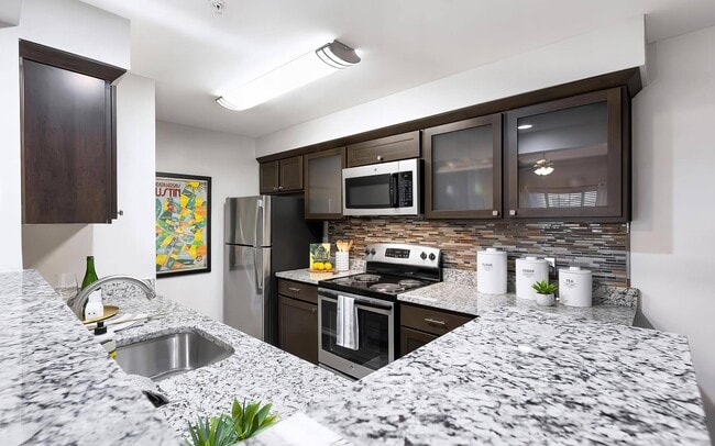 Cocina con encimeras de granito, electrodomésticos de acero inoxidable y zona de estar con barra. - Mesa Verde