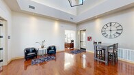 Located at 1719 Moon Meadows Dr in Rapid City, South Dakota, this single-story community facility offers a thoughtfully designed layout across a generous footprint. The space is organized into four distinct areas, each serving a specific function while contributing to an overall cohesive and polished environment.

The entry lobby immediately impresses with soaring double-height ceilings, gleaming hardwood floors, and abundant recessed lighting. A seating area with leather accent chairs provides a welcoming reception space, while a front desk area is visible through an adjacent doorway. Large windows and a glass entry door invite natural light throughout.

The lounge area features dramatic floor-to-ceiling windows that flood the room with daylight and offer outdoor views. A sleek linear fireplace with mosaic tile detailing and a wall-mounted television anchor the space, complemented by leather sofas and a central coffee table, creating a refined gathering area.

The kitchen is equipped with rich dark wood cabinetry, granite countertops, stainless steel appliances, a large island with bar seating, pendant lighting, and a decorative tile backsplash — ideal for community events and gatherings.

The fitness center is spacious and well-lit, featuring treadmills, ellipticals, stationary bikes, a power rack with free weights, and wall-mounted monitors. Natural light pours in through large windows. The facility also includes fully tiled restrooms with private shower stalls, granite vanities, and upscale tile work throughout.