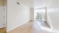 Located at 2020 Fourth Street in Berkeley, California, this one-bedroom, one-bathroom unit offers a thoughtfully designed single-level layout with a clean, modern aesthetic throughout. Light-toned bamboo hardwood flooring flows seamlessly across all main areas, complementing the bright white walls and contributing to the space's airy, welcoming atmosphere.

The open-concept kitchen anchors the living area with a peninsula counter that provides both workspace and a natural divide between cooking and living zones. Warm wood cabinetry pairs with stainless steel appliances—including a refrigerator, electric range, microwave, and dishwasher—while pendant lighting adds a stylish finishing touch. Track lighting in the living and dining area offers versatile illumination.

The combined dining and living room is bathed in natural light from large sliding glass doors and floor-to-ceiling windows that frame views of the surrounding neighborhood and greenery. The bedroom features a dedicated closet, its own large window with verdant outdoor views, and abundant natural light. A full bathroom includes a shower-tub combination, wood-toned vanity with white countertop, and a wall-mounted cabinet for storage. The unit also includes an in-unit laundry area for added convenience.