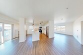 Located at 1200 Mercer St in Seattle's Lower Queen Anne neighborhood, this one-bedroom, one-bathroom residence offers a well-designed, single-floor layout with a clean, modern aesthetic throughout. The open-concept living area is anchored by large corner windows that flood the space with natural light and frame views of the surrounding Seattle cityscape and greenery. Durable hardwood-style flooring runs through the main living, dining, and kitchen areas, lending a cohesive and contemporary feel. The kitchen is well-appointed with white cabinetry, stainless steel appliances including a refrigerator, range, and microwave, track lighting, and a peninsula with pendant lights that doubles as a breakfast bar. A spacious hallway connects the main living area to the private bedroom wing, lined with multiple closets offering generous storage. The bedroom features plush carpeting, a large window with outdoor views, a dedicated closet, and a baseboard heating system. A patio provides outdoor access, rounding out this thoughtfully laid-out residence ideal for urban living in the heart of Seattle.