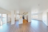 Located at 1200 Mercer St in Seattle's Lower Queen Anne neighborhood, this one-bedroom, one-bathroom residence offers a well-designed, single-floor layout with a clean, modern aesthetic throughout. The open-concept living area is anchored by large corner windows that flood the space with natural light and frame views of the surrounding Seattle cityscape and greenery. Durable hardwood-style flooring runs through the main living, dining, and kitchen areas, lending a cohesive and contemporary feel. The kitchen is well-appointed with white cabinetry, stainless steel appliances including a refrigerator, range, and microwave, track lighting, and a peninsula with pendant lights that doubles as a breakfast bar. A spacious hallway connects the main living area to the private bedroom wing, lined with multiple closets offering generous storage. The bedroom features plush carpeting, a large window with outdoor views, a dedicated closet, and a baseboard heating system. A patio provides outdoor access, rounding out this thoughtfully laid-out residence ideal for urban living in the heart of Seattle.