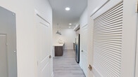 Located at 1260 NE Reserve Trail in Jensen Beach, Florida, this single-story, 3-bedroom home presents a clean, modern aesthetic defined by crisp white walls, light wood-style luxury vinyl flooring, and contemporary finishes carried consistently throughout the space.

The kitchen serves as a central highlight, featuring wood-toned cabinetry extending to the ceiling for generous storage, a white countertop island with pendant lighting in polished chrome, and a full suite of stainless steel appliances including a side-by-side refrigerator with ice and water dispenser, electric range, and built-in microwave. A white tile backsplash and recessed lighting complete the well-appointed space.

A wide hallway leads from the kitchen toward the bedrooms, with louvered storage doors providing practical utility. The bedrooms are bright and open, with one featuring a ceiling fan and a window offering natural light and exterior views. The spacious living area connects seamlessly to the primary suite via an open doorway.

The primary bathroom features a dual-sink vanity with wood-toned cabinetry, a large wall mirror, elegant light fixtures, and a tiled walk-in shower. A secondary bathroom offers a tiled tub-shower combination with chrome fixtures and matching vanity. The overall ambiance is fresh, clean, and move-in ready.