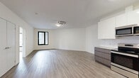 Located at 125 South Harrison Street in East Orange, NJ, this thoughtfully designed one-bedroom, one-bathroom residence offers a clean, modern aesthetic across a well-utilized single floor. Light-toned hardwood-style flooring flows seamlessly throughout, complementing the crisp white walls and creating a bright, cohesive atmosphere.

The open-concept kitchen and living area forms the heart of the unit. The kitchen is outfitted with a full suite of stainless steel appliances — including a refrigerator, electric range, microwave, and dishwasher — paired with two-tone cabinetry featuring white upper cabinets and warm wood-grain lower cabinets, white quartz-style countertops, and a classic subway tile backsplash. A ceiling-mounted HVAC cassette unit in the living area ensures year-round comfort, while a large black-framed window draws in natural light.

The bedroom is a well-proportioned retreat with clean white walls, wood-style flooring, and access to a walk-in closet alongside an additional closet for ample storage. The bathroom features a soaking tub with a glass panel enclosure, a modern floating vanity with an integrated sink, and a mirrored medicine cabinet. Additional highlights include a private balcony, a dedicated utility room, and a smart home thermostat panel. The unit combines functional design with contemporary finishes throughout.