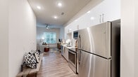 This one-bedroom, one-bathroom unit in Memphis, TN offers a smartly designed open-concept layout that maximizes every square foot. The galley-style kitchen runs along one wall and flows directly into the living area, creating a seamless, elongated living space. The kitchen is equipped with stainless steel appliances — including a full-size refrigerator, electric range, microwave, and dishwasher — complemented by crisp white upper cabinetry, light wood-toned lower cabinets, and light-colored countertops. Recessed lighting and wood-look plank flooring carry throughout the main living area, which benefits from a ceiling fan and a window that brings in natural light. The bedroom offers a cozy retreat with its own ceiling fan and direct access to a dedicated walk-in closet featuring wire shelving for organized storage. The full bathroom is finished with a granite-topped vanity with wood-toned cabinetry, a tub/shower combination with white subway tile surround, and matching wood-look flooring that ties the space together cohesively. Clean lines, neutral tones, and contemporary finishes give this unit a modern, move-in-ready appeal throughout.