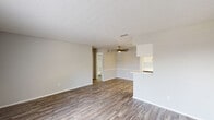 This well-appointed one-bedroom, one-bathroom unit is located at 5300–5324 Broadway Blvd in Garland, TX, offering a thoughtfully organized single-floor layout. Wood-look plank flooring runs throughout the space, lending warmth and visual continuity across every room. Neutral gray walls and white trim create a clean, modern aesthetic.

The living room is bright and welcoming, featuring a ceiling fan and a front-facing window with blinds that allows natural light to fill the space. It connects seamlessly to the kitchen via a half-wall pass-through with a countertop overhang. The kitchen is well-equipped with white shaker-style cabinetry, a subway tile backsplash, white countertops, and a full suite of stainless steel appliances including a refrigerator, dishwasher, and range.

The bedroom is a comfortable, well-proportioned room with a ceiling fan, a window overlooking outdoor greenery, and access to a dedicated closet featuring built-in shelving — offering practical and organized storage. The bathroom includes a full tub-shower combination with white tile surround, a curved shower rod, and clean white fixtures. A textured ceiling is consistent throughout the unit, adding a classic residential character to the overall space.