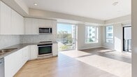 Located on the third floor at 2475 Hurontario Street in Mississauga, this contemporary 2-bedroom, 2-bathroom condo offers a well-designed open-concept layout with modern finishes throughout. Light hardwood flooring flows seamlessly across the living spaces, complemented by neutral tones that create a bright and airy atmosphere. The open-concept kitchen features sleek white cabinetry, a herringbone tile backsplash, stainless steel appliances, and generous counter space, opening directly into the sun-filled living area with floor-to-ceiling windows that invite abundant natural light and outdoor views. A private balcony with glass railings extends the living space outdoors, offering open views of the surrounding Mississauga cityscape and mature tree canopy. The primary bedroom is a comfortable retreat with mirrored sliding closet doors and a large window framing outdoor views. The second bedroom also features hardwood flooring and a mirrored closet. The two bathrooms are finished with contemporary fixtures — one featuring a glass-enclosed shower with a grey wood-tone vanity and tile flooring, and the other showcasing a deep soaker tub set against elegant marble-style tile surrounds. A hallway entry provides a practical transition into the main living areas, completing this well-appointed urban residence.