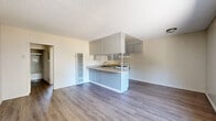 Located at 10210 Mountair Ave in Tujunga, CA, this single-story, one-bedroom, two-bathroom unit offers a practical and well-organized layout. The open-concept living and dining area is finished with light hardwood-style flooring and features a large window that allows natural light to fill the space, along with a wall-mounted AC unit for climate control. A textured ceiling runs throughout the common areas, adding a classic residential touch.

The kitchen opens directly to the living area and is equipped with gray cabinetry — both upper and lower — offering ample storage, along with light countertops, a stainless steel sink, and a white gas range. A peninsula counter extends toward the living space, providing a convenient area for dining or meal prep.

A hallway connects the main living area to the private quarters, where the bedroom features soft carpeting, a sliding-door closet, and a window dressed with vertical blinds that invite natural light. The two bathrooms include a full bath with a tub-and-shower combination enclosed by sliding glass doors and wood-style flooring. A utility panel is accessible from the hallway, adding functional convenience to the space.