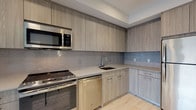 Located at 209 Revere Beach Pkwy in Revere, MA, this single-floor residence showcases a clean, contemporary design with high-quality finishes throughout. The open-concept kitchen is a standout feature, outfitted with wood-grain cabinetry extending to the ceiling, light quartz countertops, a chevron-patterned tile backsplash, and a full suite of stainless steel appliances including a range, microwave, dishwasher, and refrigerator. Light hardwood-style flooring runs through the main living areas, lending warmth and continuity to the space.

The bedrooms are carpeted and filled with natural light through well-positioned windows. One bedroom benefits from direct access to a private bathroom featuring a floating wood-toned vanity, illuminated mirror, large-format white tile flooring, and a glass-enclosed shower. A second full bathroom includes a soaking tub with tiled surround and a matching modern vanity. A walk-in closet with wire shelving provides ample storage.

A dedicated in-unit laundry closet with a stacked washer and dryer adds everyday convenience. Recessed lighting throughout maintains a bright, polished ambiance, while the neutral color palette and modern detailing give the space a fresh, move-in-ready feel.