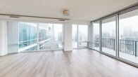 Located in the heart of Charlotte, NC, this generously sized 2-bedroom, 2-bathroom high-rise residence offers an impressive open-concept layout across a single floor. The expansive living room is defined by dramatic floor-to-ceiling glass windows that flood the space with natural light and frame breathtaking panoramic views of the Charlotte skyline and beyond. Light hardwood flooring runs throughout the main living areas, lending warmth and continuity to the open design.

The gourmet kitchen is a standout feature, outfitted with rich cherry wood cabinetry, granite countertops, a large center island, stainless steel appliances including a built-in double oven, dishwasher, and French door refrigerator, plus sleek track and pendant lighting overhead. The kitchen flows seamlessly into the living area, ideal for entertaining.

The spacious primary bedroom enjoys its own set of expansive windows with sweeping city views and plush carpeting. The primary bathroom features a glass-enclosed walk-in shower, a soaking tub, tile flooring, and warm wood vanity cabinetry with granite counters. The second bathroom mirrors this refined aesthetic with a glass shower enclosure and matching finishes. A dedicated laundry room with side-by-side washer and dryer and overhead cabinetry adds everyday convenience.