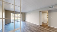 This single-floor residence offers a practical and cohesive layout across two bedrooms and two bathrooms. The living area is a notable highlight, featuring wood-look plank flooring, neutral wall tones, and a textured ceiling. Large sliding glass doors along one wall allow abundant natural light to fill the space while providing direct views of the surrounding greenery outdoors, creating a bright and open atmosphere.

The galley-style kitchen is efficiently designed with white cabinetry, light countertops, a stainless steel sink, and black appliances including an electric range and refrigerator. A window above the counter brings in additional natural light and outdoor views.

The primary bedroom is generously sized and features dual closets with sliding doors, offering ample storage. The second bedroom includes its own closet and a window that frames natural greenery. Both bedrooms continue the wood-look flooring seen throughout the unit.

Each of the two bathrooms is finished with a white tiled tub-shower combination, a white vanity with a light countertop, and wood-look flooring, maintaining a clean and consistent aesthetic throughout the residence. A hallway connects the rooms, contributing to an efficient and well-organized floor plan.