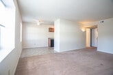 This single-floor residential unit offers a practical and comfortable layout designed for everyday living. The kitchen is equipped with rich, warm-toned cabinetry, dark granite-style countertops, a double-basin sink, and tile flooring, with a black refrigerator and ample upper cabinet storage providing both style and function. A ceiling-mounted ventilation system and overhead lighting complete the kitchen's utilitarian design.

The living area is generously proportioned, featuring plush wall-to-wall carpeting and multiple windows that allow natural light to fill the space, creating a bright and welcoming atmosphere. A ceiling fan light fixture adds comfort and practicality.

The unit includes several bedrooms, each carpeted and featuring neutral-toned walls. Multiple bedrooms are outfitted with standard closets offering dedicated storage space, and windows in each room provide natural light and outdoor views of the surrounding area.

The bathroom features tile flooring, a single-sink vanity with under-cabinet storage, a toilet, and a full-size tub and shower combination with a clean white surround. The layout is straightforward and efficient. Overall, the unit presents a clean, move-in ready environment with consistent finishes throughout.