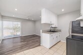 Located at 536 Linden Ave in Long Beach, CA, this one-bedroom, one-bathroom unit offers a well-organized single-floor layout designed to maximize functionality. The interior is finished with soft gray walls and clean white trim throughout, creating a cohesive and modern aesthetic.

The galley-style kitchen is a standout feature, equipped with white cabinetry, granite countertops, a double basin sink with a matte black faucet, and stainless steel appliances including a refrigerator and electric range. Light tile flooring runs through the kitchen, providing a clean contrast to the wood-look flooring found in the living and bedroom areas.

The living room benefits from recessed lighting and a ceiling fan, while a sliding glass door with horizontal blinds invites natural light and provides outdoor access. The bedroom is a comfortable size, also featuring wood-look flooring, a ceiling fan with recessed lighting, and a window with blinds that allows for natural light.

The bathroom is clean and functional, outfitted with a full tub-shower combination, a white vanity with an oil-rubbed bronze faucet, and a mirror cabinet. A hallway connects the rooms efficiently, with additional windows ensuring consistent natural light flows through the entire unit.