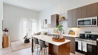 Located at 200 Rood Ave in Grand Junction, Colorado, this thoughtfully designed one-bedroom, one-bathroom unit offers a clean, modern aesthetic throughout. The open-concept layout seamlessly connects the kitchen and living area, maximizing the efficient use of space while maintaining an inviting, airy atmosphere. Tall ceilings and crisp white walls amplify the sense of openness, while light wood-tone flooring runs throughout, providing a warm and cohesive base.

The kitchen is a standout feature, showcasing rich walnut-toned cabinetry, a striking herringbone-pattern tile backsplash, quartz countertops, and stainless steel appliances including a dishwasher, range, microwave, and refrigerator. A central kitchen island with bar seating serves as both a functional workspace and a casual dining area. A dedicated entryway nook with built-in hooks and a shelf provides convenient storage upon arrival.

The living area is bright and welcoming, anchored by a large sliding glass door with vertical blinds that fills the space with natural light. The bedroom features soaring ceilings, a ceiling fan, a generous window with natural light, and ample space for a full furniture arrangement. The bathroom and a closet round out this well-appointed unit, delivering practical functionality in a stylish, contemporary package.