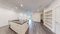 Located at 95 Maple St in Stoneham, MA, this thoughtfully designed one-bedroom, one-bathroom residence offers a clean, modern aesthetic with high-quality finishes throughout. The open-concept kitchen and living area serves as the heart of the home, showcasing a large center island with a dark stone countertop, undermount sink, and ample seating space. The kitchen features floor-to-ceiling white cabinetry, a marble-style backsplash, and stainless steel appliances, all illuminated by recessed lighting. Rich, wide-plank hardwood flooring flows seamlessly throughout the main living areas. Sliding glass doors in the living space lead to a private balcony with outdoor views, filling the interior with natural light. The bedroom is a calm, well-proportioned retreat with a ceiling fan, a window with outdoor views, and access to generously sized closets equipped with wire shelving systems. The bathroom offers a spa-like atmosphere with large-format marble-style tile flooring, a floating vanity with a dark stone countertop, a framed mirror, and a soaking tub. Additional conveniences include an in-unit laundry area and built-in shelving. The residence presents a cohesive, contemporary design with a bright, neutral palette throughout.