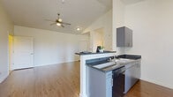 This thoughtfully designed 2-bedroom, 2-bathroom single-story residence offers a comfortable and functional layout across a well-utilized floor plan. The open-concept living and dining area is highlighted by soaring vaulted ceilings and a ceiling fan, creating an airy, spacious feel. Warm wood-look flooring flows throughout the main living spaces, complementing the bright, neutral-toned walls.

The kitchen features sleek gray cabinetry, dark granite-style countertops, stainless steel appliances including a full-size refrigerator and dishwasher, and a peninsula with bar seating that opens directly to the living area. A door with adjacent windows allows natural light to fill the kitchen and provides exterior access.

Both bathrooms are finished with hexagonal tile flooring, dark countertops, modern cabinetry, and full tub-shower combinations with curtain rods. A large vanity mirror enhances each bathroom's sense of space.

The bedrooms are carpeted for comfort, with the spacious primary bedroom offering generous square footage. The secondary bedroom includes a sliding-door closet. A dedicated laundry area and a utility space housing a water heater round out the home's practical amenities, ensuring all essential functions are neatly contained within the layout.