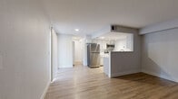 Located at 1121 W Prospect Rd in Fort Collins, CO, this one-bedroom, three-bathroom unit offers a thoughtfully designed single-floor layout that maximizes functionality. The open-concept living and kitchen area creates a bright, cohesive space anchored by light wood-style flooring and a neutral gray and white color palette. The kitchen features a peninsula-style breakfast bar, white and gray cabinetry, stainless steel appliances including a full-size refrigerator and microwave, a stainless sink, and track lighting overhead — offering both practicality and a clean, modern aesthetic. The living area is spacious and open, with a sliding glass door that invites natural light. A dedicated entry area provides a welcoming transition into the home. The bedroom is comfortably sized, carpeted for warmth, and includes a closet and a window with natural light. A hallway connects the bedroom to the bathrooms, one of which features a full tub-shower combo with white subway tile surround. A stacked washer/dryer is conveniently accessible from the hallway. The overall design is clean and contemporary, making this a well-appointed unit suited for comfortable everyday living in a prime Fort Collins location near Colorado State University.