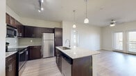 Located at 7035 Pickwell Drive in San Antonio, TX, this two-bedroom, two-bathroom residence offers a well-designed single-level layout with a clean, modern aesthetic throughout. Light wood-style flooring flows seamlessly through the entire space, complementing the neutral, warm-toned walls that create a bright and welcoming atmosphere.

The open-concept kitchen and living area serves as the heart of the home. The kitchen is outfitted with rich dark espresso cabinetry, granite countertops, a tile backsplash, and a full suite of stainless steel appliances including a refrigerator, range, and built-in microwave. A central island with a sink and pendant lighting above adds both function and style, while a dedicated hallway connects the main living areas to the private quarters.

Both bedrooms are comfortably sized, featuring ceiling fans, natural light from windows with blinds, and the same continuous flooring. The primary bedroom includes access to a private balcony that overlooks open green space, offering a peaceful outdoor retreat with expansive sky views.

The two bathrooms are finished with dark cabinetry, granite vanity tops, and light tile flooring. The primary bath features a spacious layout with a large vanity and walk-in shower area, while the secondary bath includes a full tub-shower combination. A connecting hallway provides practical flow between all rooms.