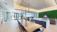 Located at 45 Seacoast Terr in Kittery, Maine, this single-floor amenity center spans a generously sized footprint designed to serve as a multifunctional community hub. The interior design blends contemporary aesthetics with natural elements, creating a polished yet welcoming atmosphere throughout.

The main lounge and social area is anchored by a large communal dining table with herringbone-patterned light wood flooring underfoot. An eye-catching geometric pendant lighting installation hangs from a coffered ceiling with warm wood trim, adding architectural sophistication. A dramatic living moss wall serves as a central design feature, framing a mounted flatscreen TV and providing a vibrant natural focal point. Comfortable leather sectional seating and accent chairs, including a hanging egg chair, complete the relaxed gathering areas.

A dedicated conference room offers a streamlined wood table, pendant lighting, wall-mounted display, built-in cabinetry with a sink, and exterior window views — ideal for private meetings.

The fitness center is expansive, featuring a full array of strength and cardio equipment, rubber flooring, exposed beam ceilings, and a striking cartographic mural across a deep navy accent wall, contributing both energy and local character to the space.