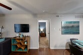Located in Houston, TX, this efficiently designed one-bedroom, one-bathroom single-story residence offers a well-organized layout that maximizes every square foot. The living room serves as the social heart of the home, featuring rich hardwood flooring, a ceiling fan with light fixture, and French doors that flood the space with natural light while providing access to the patio. The kitchen is outfitted with dark espresso cabinetry, light countertops, a double-basin sink, and black appliances, opening directly to a dedicated dining area that comfortably accommodates a round table and chairs. The bedroom is a calm retreat highlighted by a bold blue accent wall, plush carpet, a ceiling fan, and windows dressed with blinds and draping curtains that allow for adjustable natural light. A closet provides convenient storage within the bedroom. The full bathroom features a tiled shower-tub combination with clean white finishes. Throughout the residence, neutral gray walls and consistent hardwood flooring in the main living areas create a cohesive and modern aesthetic. The included patio extends the living space outdoors, rounding out this functional and stylish Houston home.