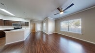 This single-floor residence offers a thoughtfully designed layout that balances open communal spaces with comfortable private areas. The living and dining area is anchored by rich, dark hardwood-style flooring that extends throughout the main living spaces, complemented by crown molding and ceiling fans that add a polished, finished look. Multiple windows fitted with blinds allow natural light to fill the rooms while offering views of the surrounding outdoors.

The kitchen is well-equipped with dark espresso-toned cabinetry, light quartz-style countertops, and stainless steel appliances including a range and over-the-range microwave. The open-plan design connects the kitchen seamlessly to the living area, enhancing the sense of space and flow.

The bedrooms feature neutral-toned carpet and windows that bring in natural light. One bedroom benefits from direct access to a spacious walk-in closet outfitted with wire shelving and hanging racks, providing generous storage. The bathroom is clean and functional, featuring a tiled tub-shower combination, dark wood vanity cabinetry, a stone-look countertop, and matching hardwood-style flooring that ties the space together cohesively throughout.