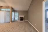 This single-floor residence offers a well-designed layout with a variety of functional and inviting spaces. The living room is a standout, featuring soaring vaulted ceilings, a classic white brick fireplace, and plush carpeted flooring. A sliding glass door with vertical blinds opens to a private balcony, while a transom window above floods the room with natural light and treetop views. A ceiling fan completes the space with added comfort and airflow.

The kitchen is efficiently designed with white shaker-style cabinetry, granite-look countertops, and light wood-style vinyl flooring. Black appliances — including a refrigerator, electric range, over-the-range microwave, and dishwasher — provide a clean contrast against the bright cabinetry. A stainless steel sink and a window above the counter bring in additional natural light.

The bedrooms are generously sized, each finished with soft carpeting and large windows overlooking lush greenery. One bedroom features a walk-in closet with built-in shelving, offering excellent storage. A second bedroom includes direct balcony access via a sliding glass door.

The bathroom is clean and functional, with a wide vanity, granite-look countertop, a large mirror, and a full tub-shower combination with chrome fixtures and wood-style flooring.