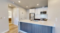 Located at 1960 Argentine St in the historic mountain town of Georgetown, Colorado, this well-appointed one-bedroom, one-bathroom unit offers a thoughtfully designed single-floor layout with modern finishes throughout. Light-toned hardwood-style flooring runs seamlessly across the space, complementing the clean, neutral color palette.

The kitchen is a standout feature, showcasing a large peninsula with a white quartz countertop and stylish blue-gray cabinetry below. Upper white cabinetry provides generous storage, while a classic white subway tile backsplash, stainless steel refrigerator, range, microwave, and dishwasher complete the contemporary look. A wall-mounted mini-split unit ensures efficient climate control.

The living area connects naturally to the kitchen, creating an open and functional layout. The bedroom offers a comfortable footprint with a built-in sliding-door closet and soft neutral walls. An additional closet provides further storage convenience. The bathroom features a walk-in shower with brushed nickel fixtures, a wood-toned vanity with a white countertop, and tile flooring that echoes the home's modern aesthetic.

Additional highlights include in-unit laundry, a private balcony, and a hallway that connects all spaces efficiently. The overall ambiance is clean, modern, and move-in ready.