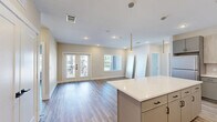 Located in Spring, Texas, this well-appointed single-story home offers three bedrooms, two bathrooms, and three closets within a thoughtfully designed floor plan. Light-toned luxury vinyl plank flooring flows consistently throughout the living areas and bedrooms, complementing the neutral warm-beige color palette that creates a bright, cohesive ambiance.

The open-concept kitchen is a standout feature, showcasing two-tone cabinetry with light wood upper cabinets and gray lower cabinets, a vertical subway tile backsplash, white quartz countertops, stainless steel appliances, and a large central island with pendant lighting above. The kitchen connects seamlessly to the living area, which features recessed lighting and French doors that invite natural light.

The primary bedroom is generously sized with a ceiling fan, and its ensuite bathroom includes marble-look porcelain tile flooring, a glass-enclosed walk-in shower with matte black fixtures, and direct access to a walk-in closet with built-in shelving and double hanging rods. The secondary bathroom features the same marble-look tile and a soaking tub with a shower combo. Additional bedrooms are bright and airy, benefiting from multiple windows with outdoor views.