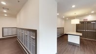 This residential common area serves as a functional and thoughtfully designed mail room and lobby space. The layout spans a single floor and is anchored by multiple banks of stainless steel individual mailboxes mounted along the walls, providing convenient mail access for a large number of residents. The flooring throughout is a rich, dark hardwood-style material that adds warmth and a polished aesthetic to the space.

Recessed ceiling lighting illuminates the area evenly, complemented by natural light streaming in through a large multi-pane window. A vibrant landscape painting in shades of green and gold adorns one wall, adding a welcoming artistic touch to the otherwise clean, neutral interior. The walls are finished in crisp white with dark wood-toned baseboard trim that ties the design together cohesively.

A white granite or stone-topped counter surface is visible near the mailbox area, offering a convenient workspace for residents sorting through mail. A metal-railed stairwell with a dark handrail connects this level to adjacent floors, featuring a sleek, modern design that complements the overall aesthetic. Dark double doors near the stairwell landing, marked with an exit sign, provide clear and accessible egress. The space is clean, modern, and efficiently organized for high-traffic residential use.